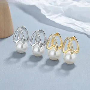 Vue macro de boucles d'oreilles perles en argent 925 et or avec zircone scintillante
