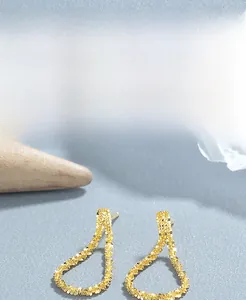 Detail of 925 sterling silver golden teardrop earrings with textured grain finish