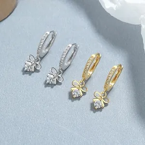 Macro view of gold and silver bow earrings with zircon stones and micro-pave crystals