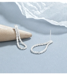 Detailed view of sterling silver glitter texture stud earrings on a wooden cone display