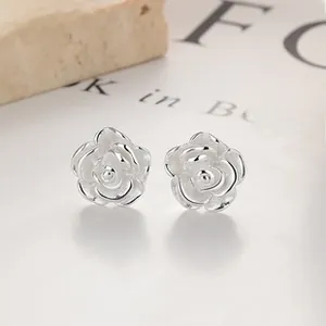 Macro view of 999 sterling silver lotus stud earrings on a textured stone and book