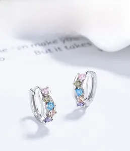 Macro detail of 925 sterling silver hoop earrings set with five colorful round zircons