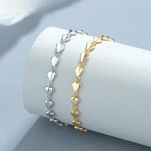 Detail of silver and gold heart link bracelets wrapped around a grey column stand