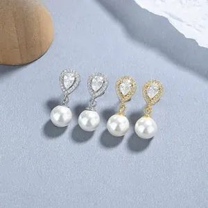 Detail of teardrop zircon and round pearl earrings in gold and silver plating