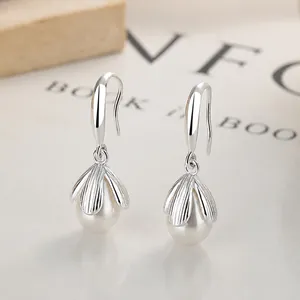Elegant 925 sterling silver flower pearl drop earrings on a minimalist wooden background