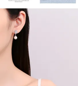 Detailed view of sterling silver pear-shaped drop earrings with pearl on a model