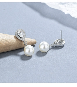 Macro view of teardrop diamond pearl earrings featuring elegant 925 silver finish