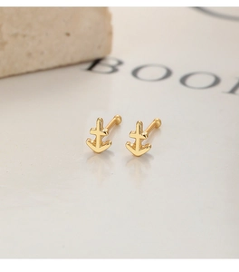 Vue macro de boucles d'oreilles ancre dorées avec finition polie et fermoir boule