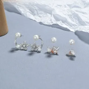 Details von Kamelien-Perlenohrringen in Silber und Roségold mit Kristallen auf grauem Grund