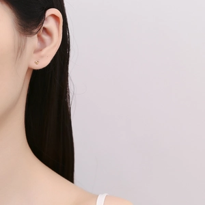 Boucles d'oreilles cœur minimalistes en argent 925 doré portées sur le lobe d'oreille