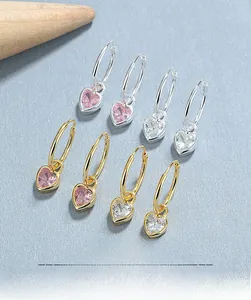 Flat lay of 925 silver and gold heart earrings with pink and white cubic zirconia