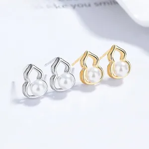 Detailed close-up of gold and silver hollow gourd stud earrings with embedded pearls