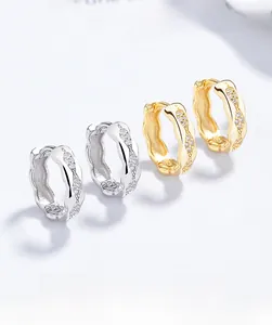 Macro detail of wave-shaped S925 sterling silver hoop earrings with sparkling zircon pave