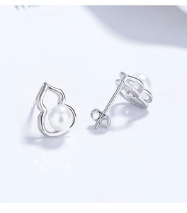 Macro detail of 925 silver hollow gourd stud earrings with elegant white round pearls