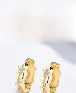 Detailed macro view of gold plated S925 sterling silver wave earrings with sparkling zircon