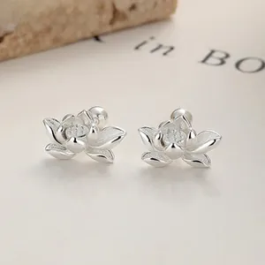 Macro detail of 925 sterling silver lotus stud earrings with screw back on a magazine