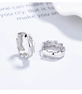 Macro shot of S925 sterling silver hoop earrings with wavy edges and pavé diamond detailing