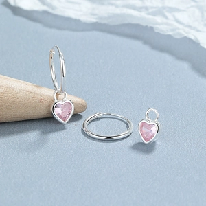 925 silver hoop earrings with detachable pink heart-shaped zirconia pendants on textured background