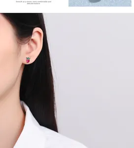 Close-up of small strawberry stud earring with red heart and green marquise gems