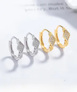 Close-up of gold and silver rhicombus earrings with sparkling pavé crystals