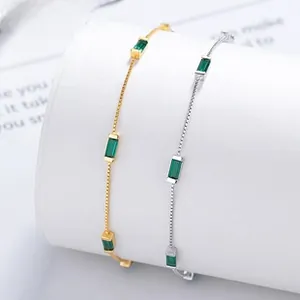 Macro view of gold and silver fine bracelets with emerald-cut green cubic zirconia stones