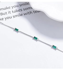 Close-up of minimalist 925 silver chain with three emerald-cut green zircons