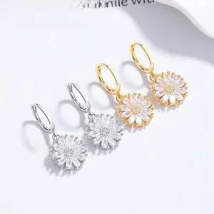 Close-up of daisy earrings in gold and silver finish with sparkling zircon petals