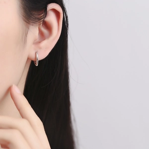 Gros plan d'une boucle d'oreille créole V en argent sterling 925 portée par un modèle