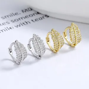 Macro view of leaf-shaped silver and gold hoop earrings with pavé-set cubic zirconia