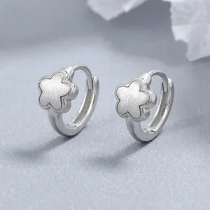 Détail macro de boucles d'oreilles fleur argentées avec fini mat et poli brillant