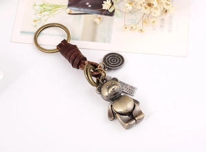 Detailed macro of vintage bronze metal bear keychain with brown leather wrap on white