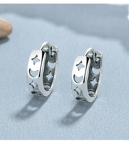 Macro shot of 925 sterling silver huggie earrings with hollow star and moon patterns
