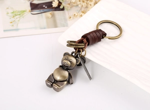 Detail of vintage bronze bear pendant with dark brown braided leather keychain loop