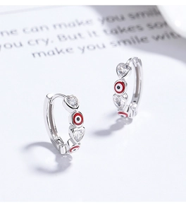 Détail macro de boucles d'oreilles en argent 925 avec zircons cœur et yeux protecteurs