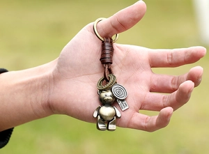 Close-up of vintage bear keychain with woven leather strap and engraved metal charm tag