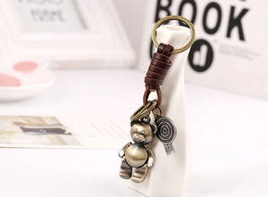 Detail of vintage bronze bear keychain with leather wrap and rustic metal charms