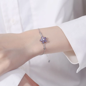 Bracciale in argento 925 con fiore di zircone viola sul polso di una donna con camicia