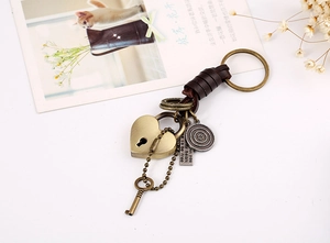 Detail of vintage leather keychain with heart lock, key pendant and engraved metal charms