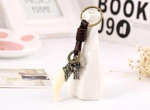 Detail of vintage leather keychain with wolf tooth pendant and bronze wolf head charm