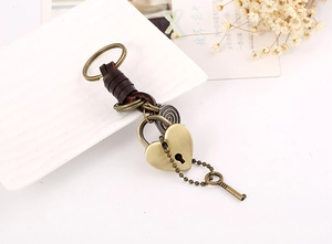 Close-up of vintage bronze heart padlock and key on dark brown braided leather keychain