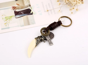 Close-up of vintage bronze wolf head keychain with woven leather rope and engraved metal tag