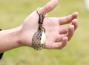 Detailed view of a vintage bronze bird embossed keychain with dark brown leather wrap