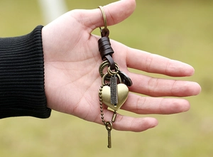 Close-up of vintage bronze heart lock keychain with genuine leather and key charm detail