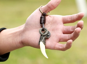 Detail of vintage punk leather keychain with bronze wolf head and resin fang charm