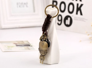 Detail of vintage soldier keychain with bronze metal and brown leather on a white vase