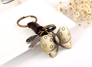 Detailed close-up of retro bronze butterfly keychain with leather wrap and charms