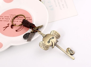 Macro shot of bronze elephant keychain with braided leather cord on vintage ceramic plate