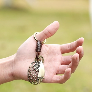 Vintage leather keychain with brass bird pendant held against a natural background