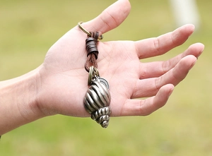 Détail du pendentif conque en métal vintage avec cordon de cuir tressé porte-clés