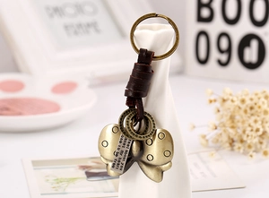Detail of vintage woven leather keychain featuring a bronze butterfly charm and engraved plate